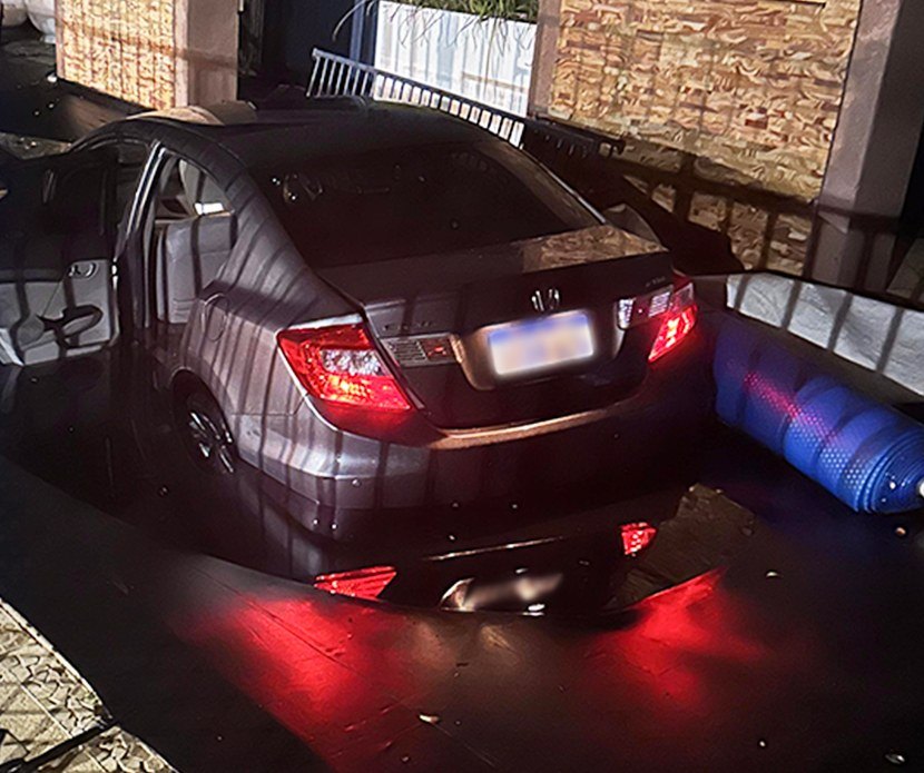 A customer's sedan sitting on a Super Mesh cover after going into a backyard pool at night