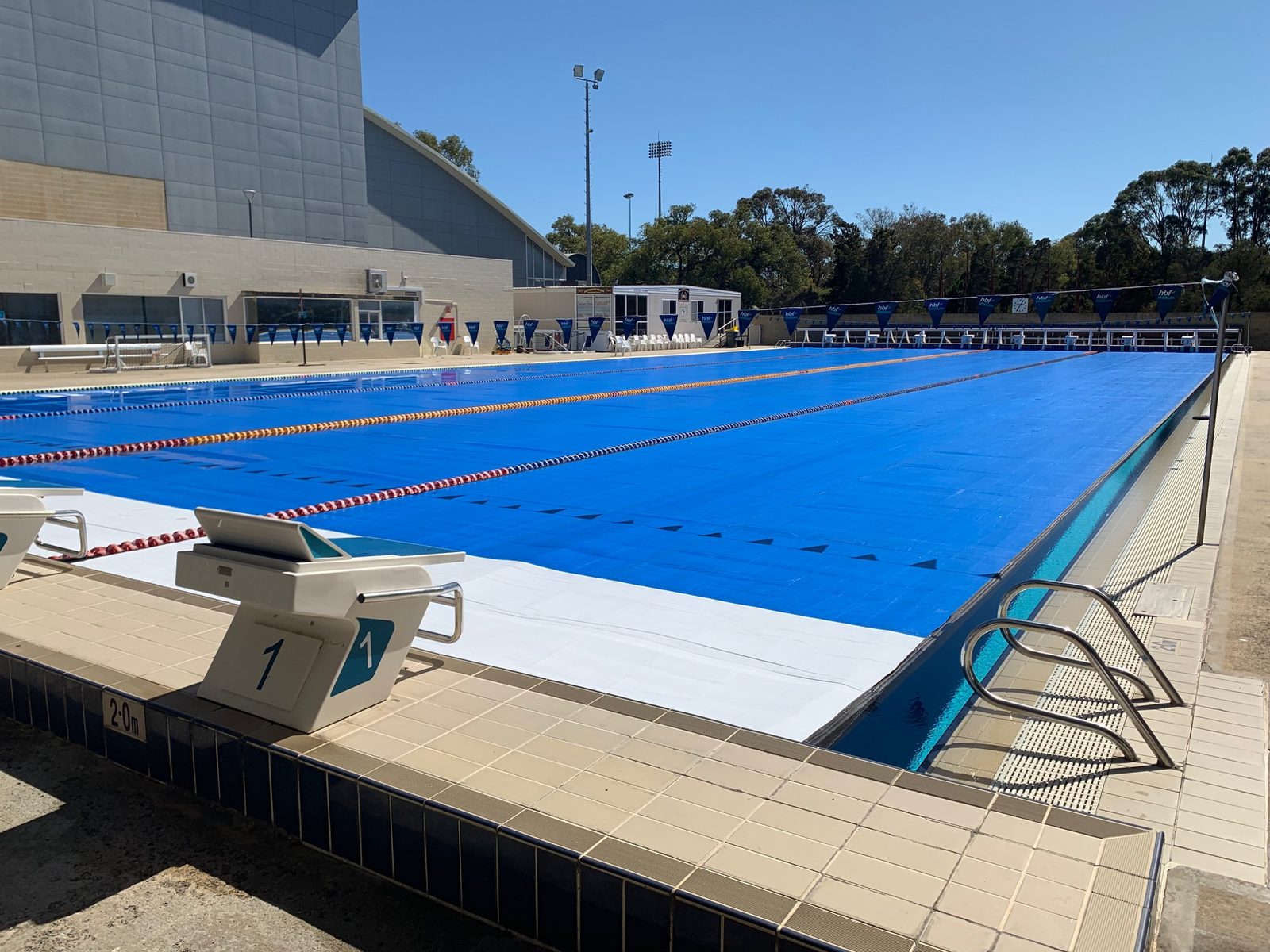 Elite commercial pool cover fully deployed across an outdoor 50m pool
